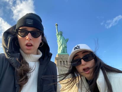 Billede af to piger, der tager en selfie med Frihedsgudinden i USA, et spændende øjeblik under et udvekslingsår i USA.